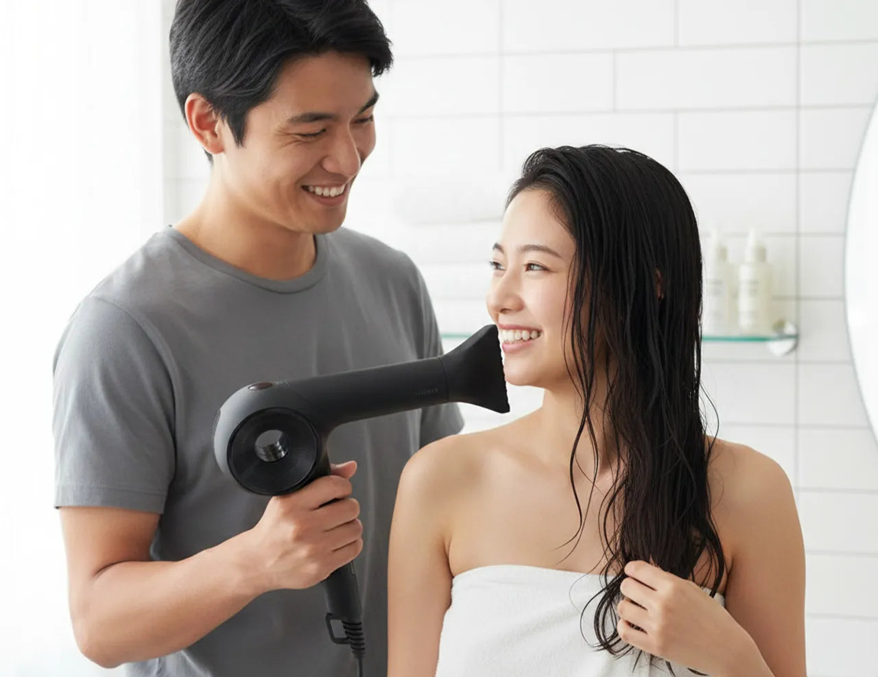 男性が女性の髪を乾かそうとドライヤーを持っている